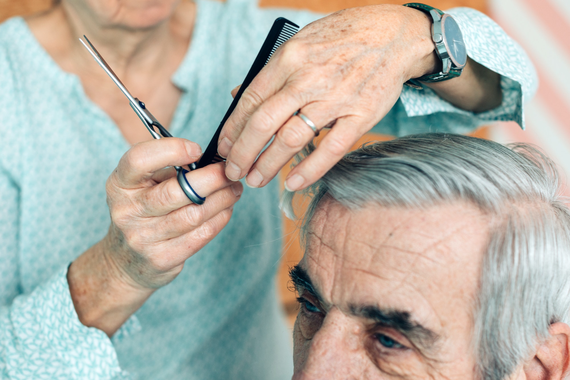 hands of elderly woman haircuts a senior man