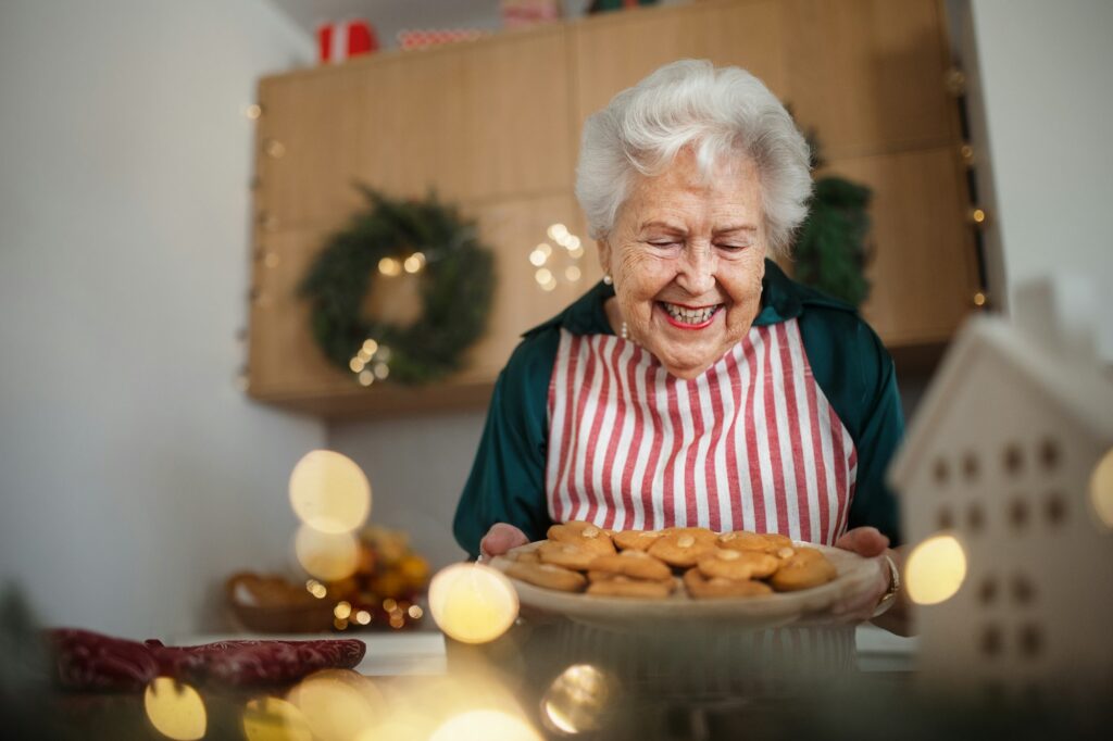 Happy senior woman baking Christmas cakes at home.